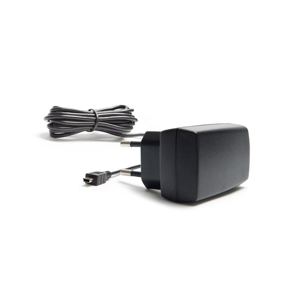 Black wall charger with two round prongs and attached cable, lying next to a coiled wire on a white background.
