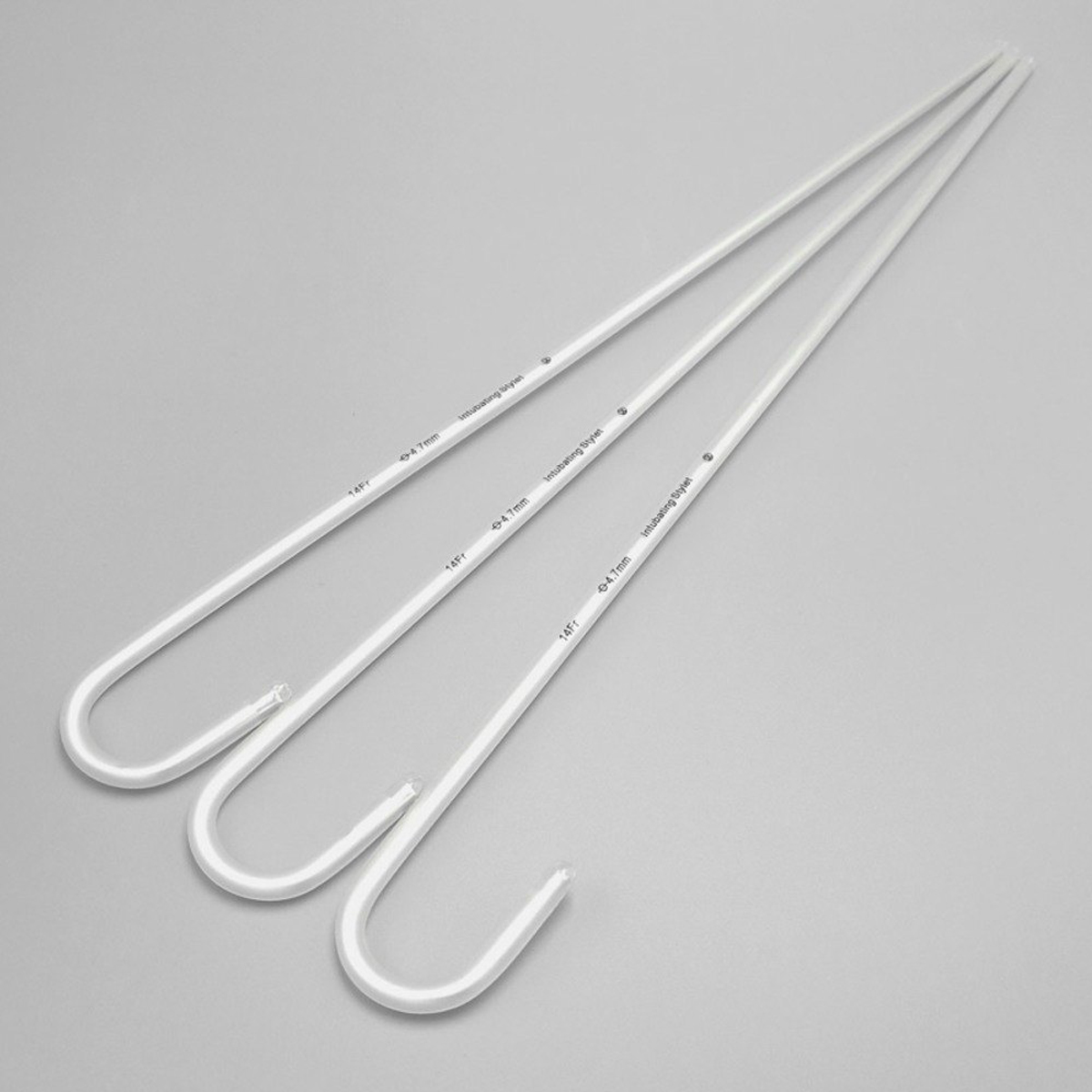 Three long white medical guidewires with curved ends on a plain gray background.