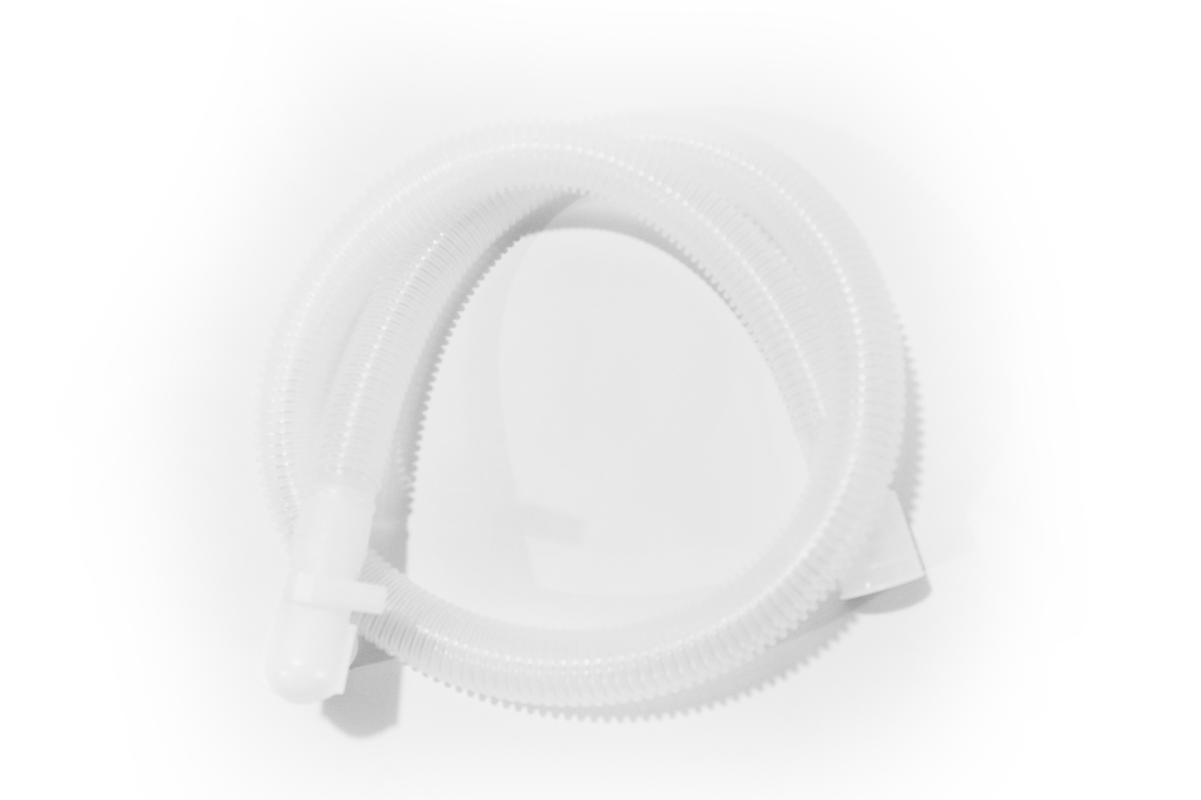 Coiled translucent corrugated plastic tube with connectors on both ends, placed on a white surface.