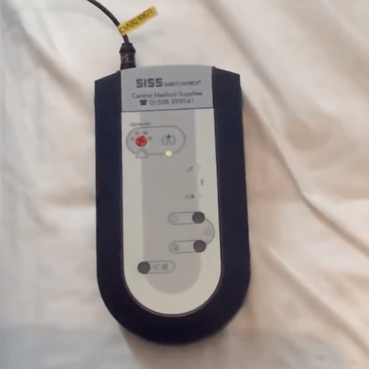 A SISS SafeControl device from Carmel Medical Supplies on a white fabric background, with indicator lights and buttons.