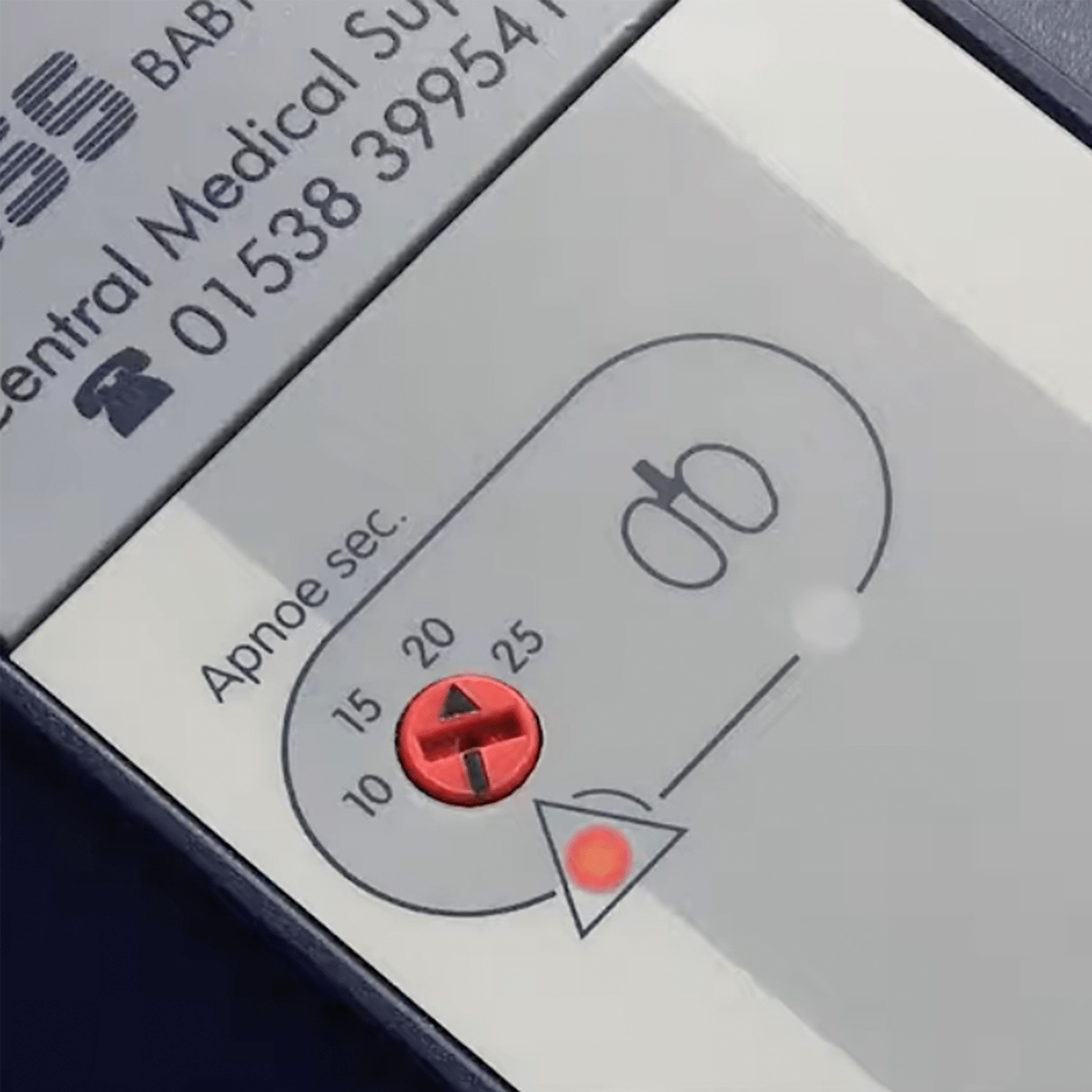 Close-up of a medical device display with a red dial, labeled "Apnoe sec." and a lit indicator light.