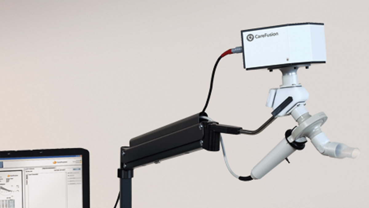 A spirometer medical device by CareFusion is mounted on an adjustable arm, next to a computer monitor.