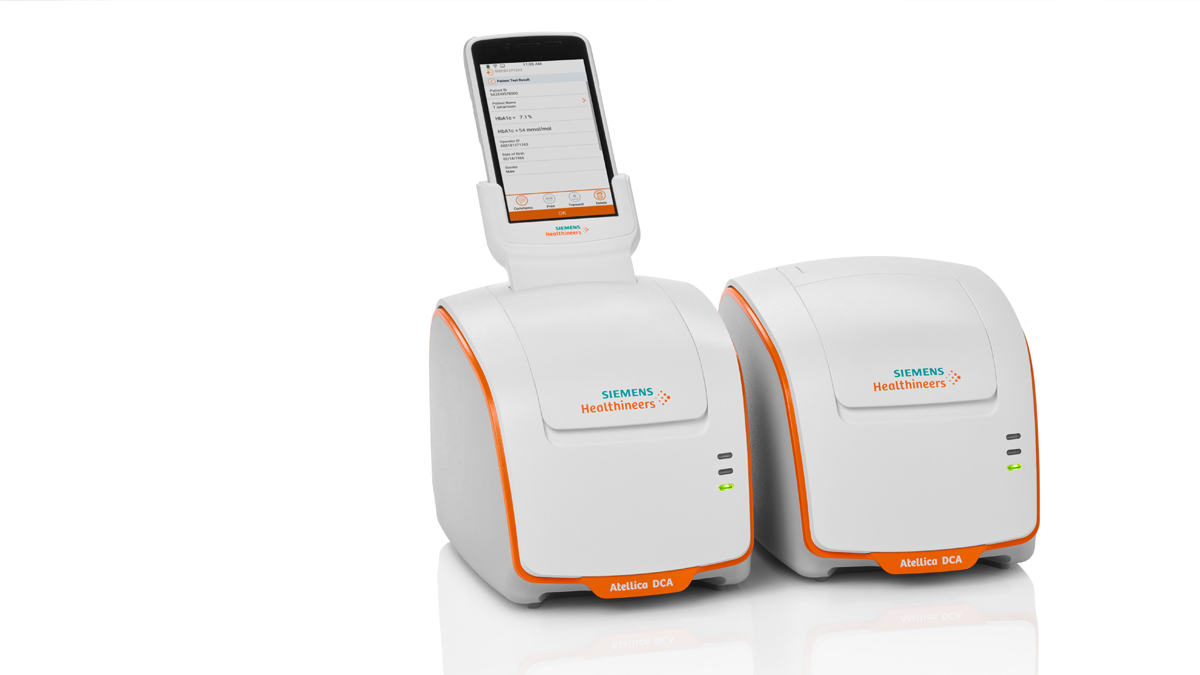 Two Siemens Healthineers Atellica DCA analyzers, one with a smartphone docked on top, on a white background.