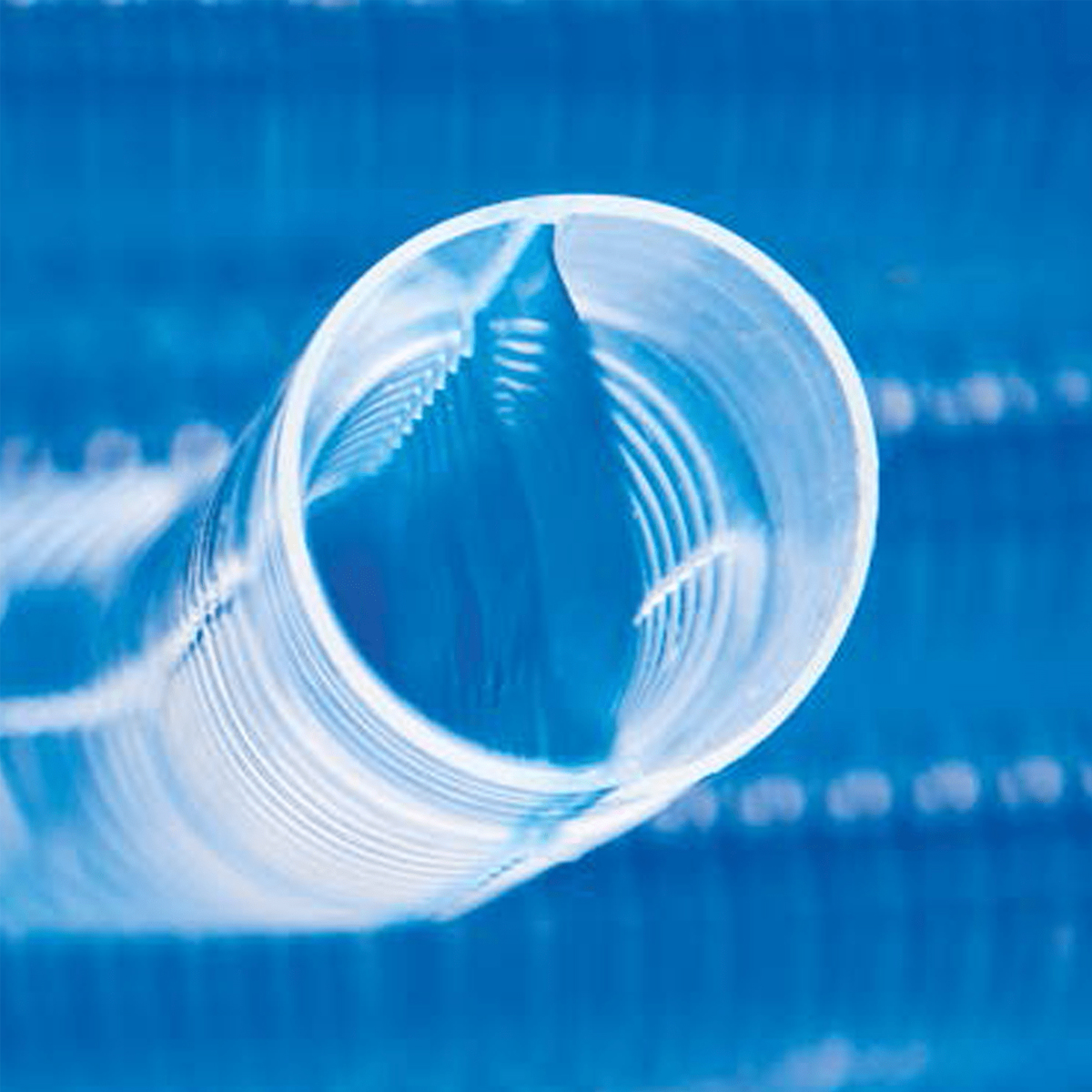 A close-up shot of a clear plastic tube with a spiral texture against a blue background.