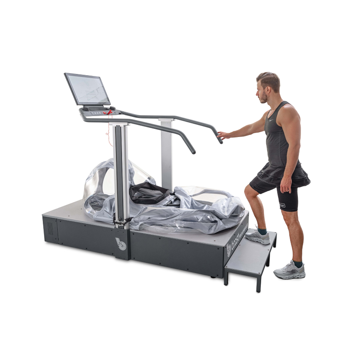 Man in athletic wear stands by an anti-gravity treadmill with a screen and transparent chamber.