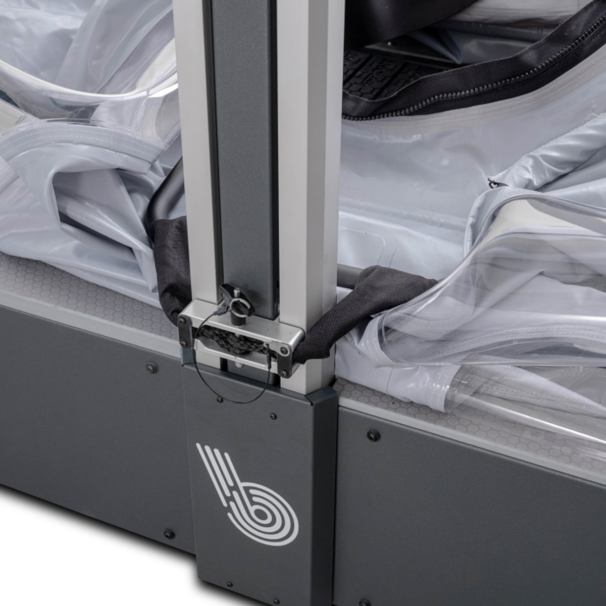 Close-up of a metal support frame attached to a clear plastic enclosure with a zipper and a black strap.